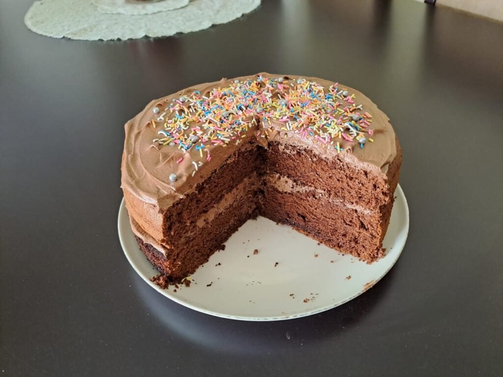 A delicious homemade chocolate cake with a rich chocolate frosting, layered and topped with colorful sprinkles. Perfect for any occasion, this cake is available at Lallie's Sweetness, your local home baking shop offering the best and most affordable cakes near you.